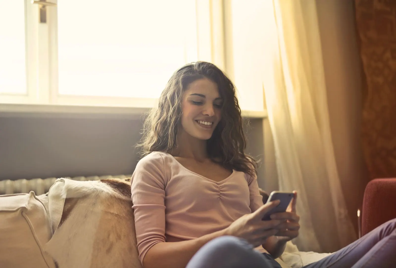A smiling woman relaxing at home and scrolling on her phone