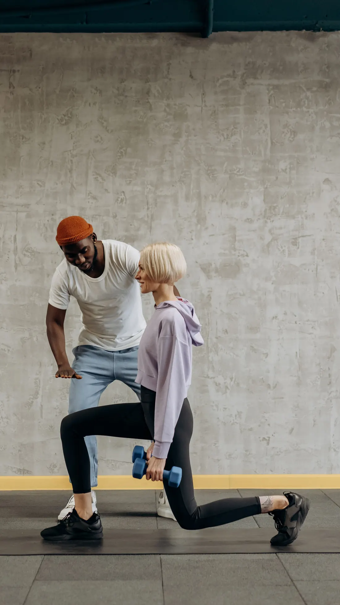 A trainer guiding a client through a dumbbell lunge