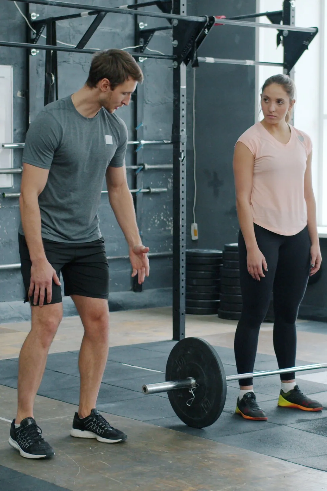 A trainer and client talking beside a barbell in a gym